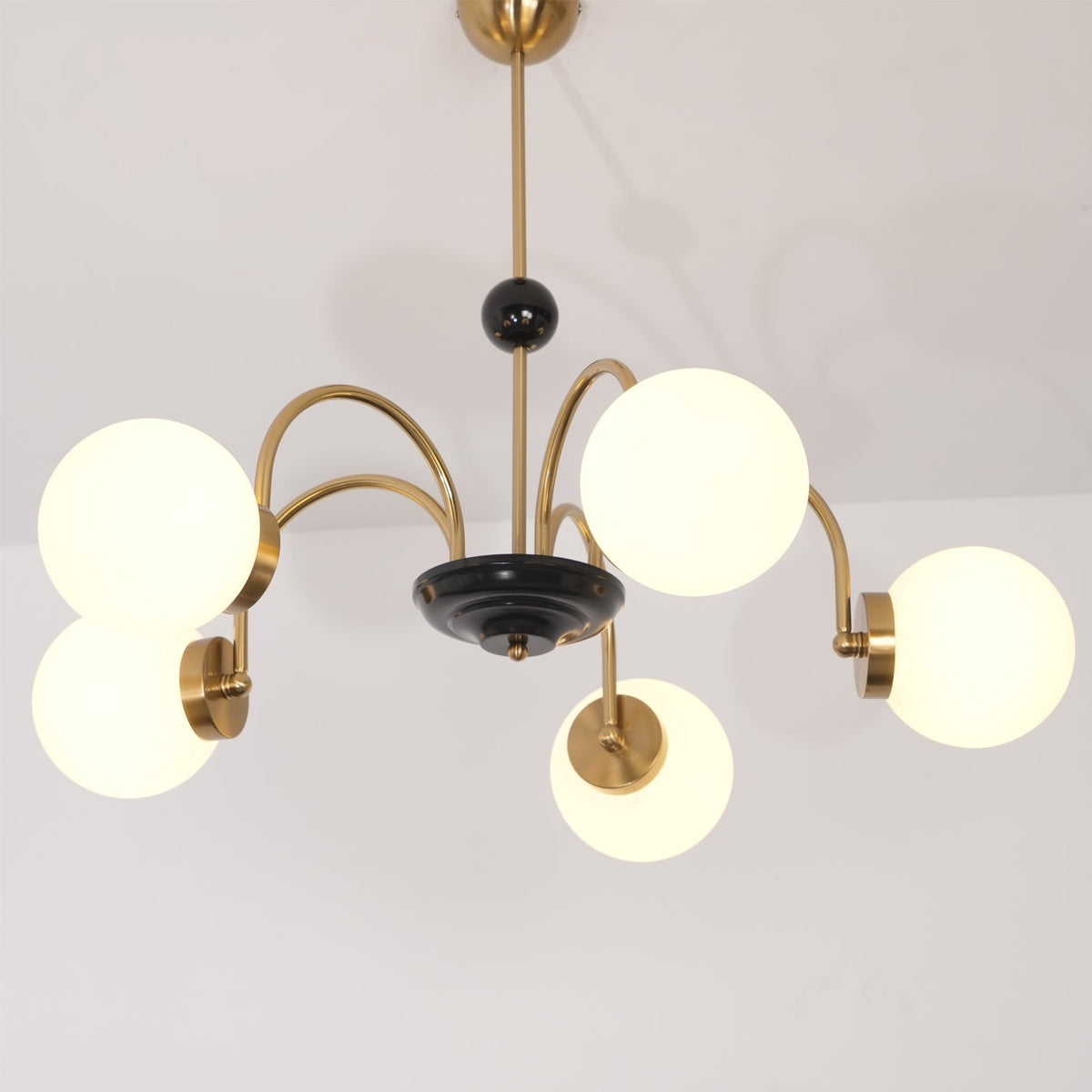 Moderne kroonluchter met gebogen armen en bolvormige kapjes, retro stijl voor eetkamer