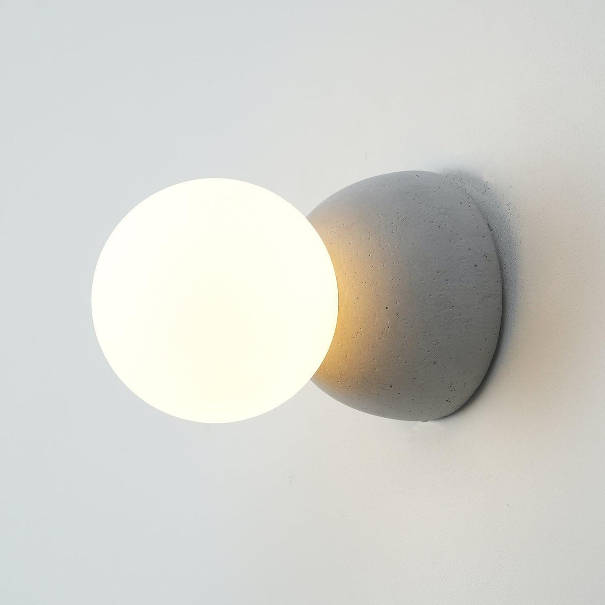 Eirinise wandlamp van beton en melkglas