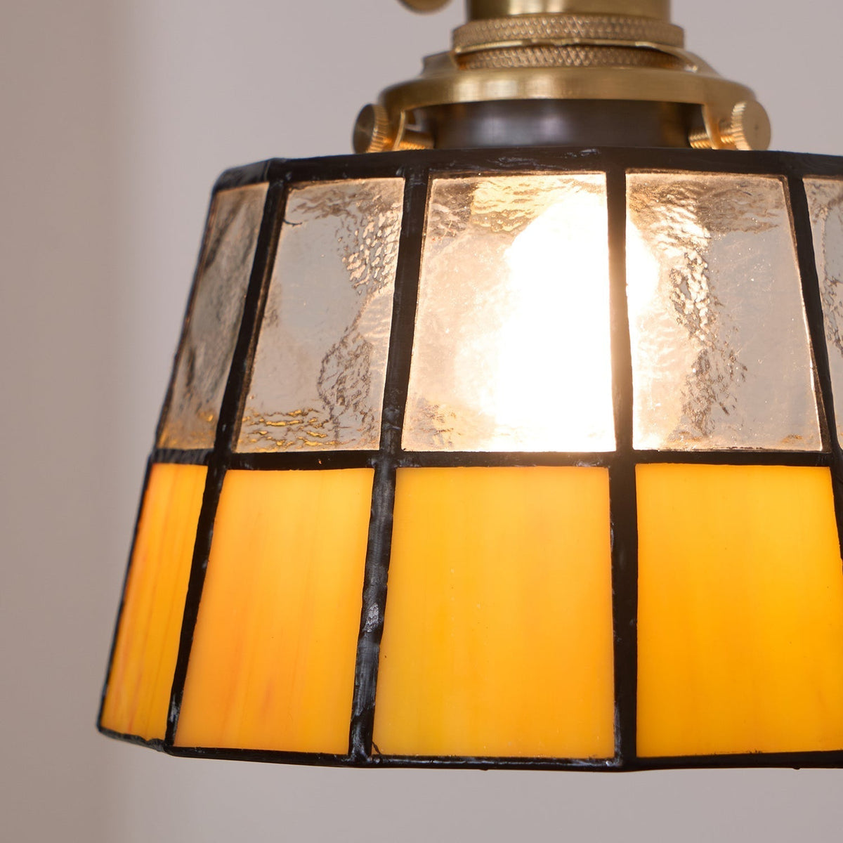 Hanglamp met verkleurd glazen kap in vintage patroon van messing